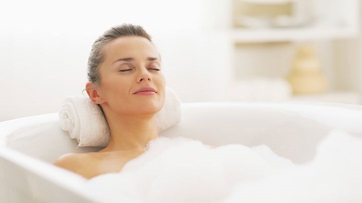 Woman relaxing in a bathtub to ease symptoms of chronic hives.