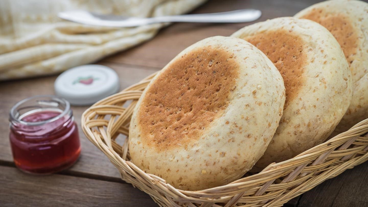 a basket of whole-grain english muffins with jelly on the side