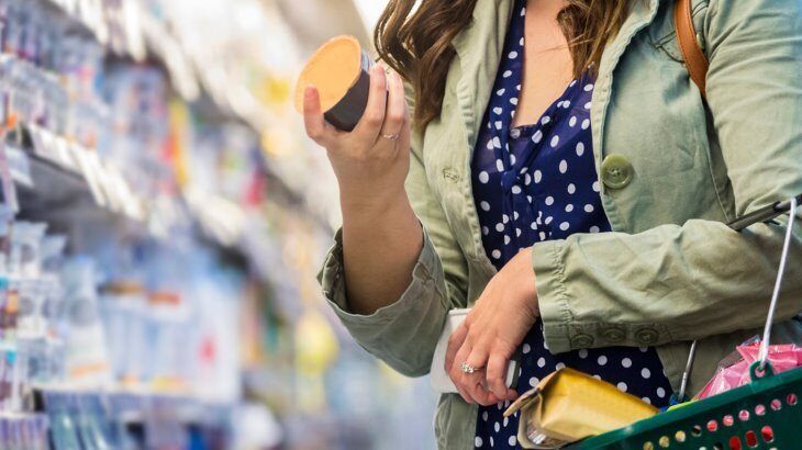 a woman looking at a food label in a grocery store